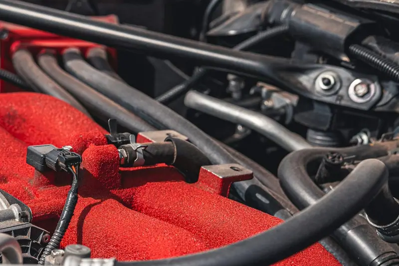Engine bay with a wiring connector on a red intake manifold
